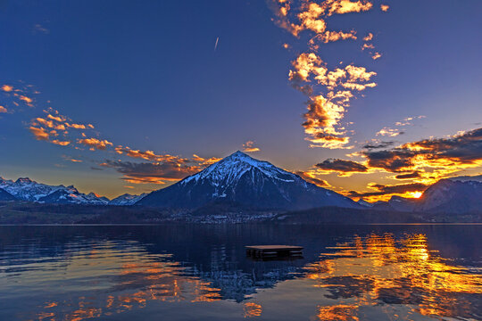 Splendid sunset over the Niesen Mountain (socalled Swiss Pyramid) with its shape reflection on Lake Thun