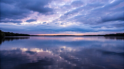 Serene lake reflecting beautiful cloudy sky during twilight hour in nature