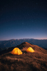 Camping adventure at sunset over mountain landscape with yellow tents under starry sky in nature's embrace