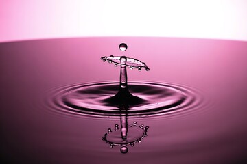 Stunning abstract water splash captures dynamic fluid motion with delicate droplets and ripples in soft pink light