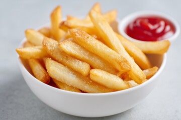 Crispy French Fries in White Bowl with Ketchup on Sage Surface