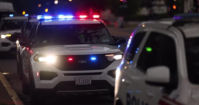 Police units respond to the scene of an emergency with illuminated red and blue lights at dusk.