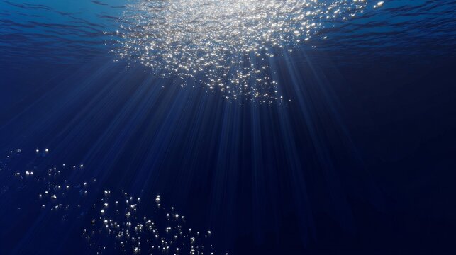 Sunlight beams penetrate clear ocean water, creating bright shafts that descend into the depths.
