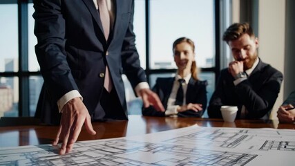 Businessman pointing at blueprint. Male business professionals meet at a meeting. A group of people are discussing blueprints on a table in an office. Entrepreneur gesturing towards a lifestyle. - Powered by Adobe