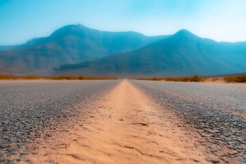 Open road stretching towards distant mountains under a clear blue sky, evoking adventure and freedom