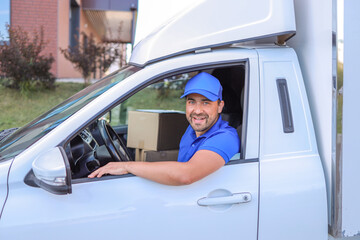 Close-up portrait male courier in blue uniform and baseball cap in white cargo van preparing. concept delivery of goods, courier service