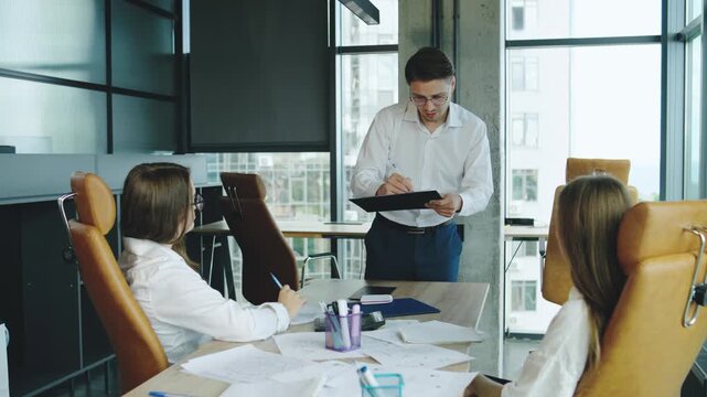 Business meeting in modern office with team discussing project details in a collaborative atmosphere during daytime
