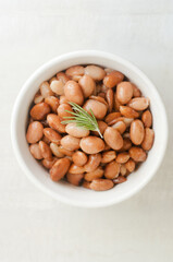Boiled borlotti beans in a white bowl on a gray background. Italian cuisine. Vegan and vegetarian food. Selective focus. Vertical orientation. Top view