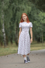 Fototapeta premium Young beautiful girl in a light dress having fun outdoors on a summer day.