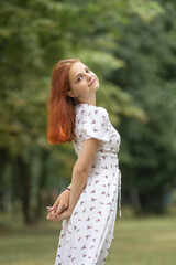 Fototapeta premium Young beautiful girl in a light dress having fun outdoors on a summer day.
