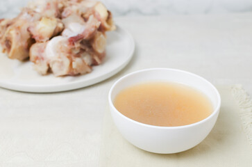 Veal bone broth in a white bowl on a white table. Collagen concept. Selective focus. Horizontal orientation. Copy space