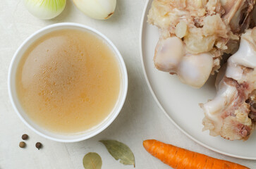 Veal bone broth in a white bowl with ingredients on a white table. Collagen concept. Selective focus. Horizontal orientation. Top view