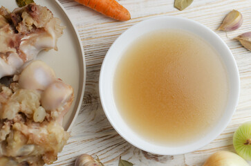 Veal bone broth in a white bowl with ingredients on a white table. Collagen concept. Selective focus. Horizontal orientation. Top view