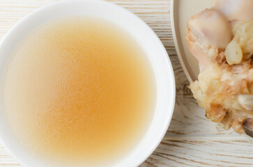Veal bone broth in a white bowl on a white table. Collagen concept. Selective focus. Horizontal orientation. Top view