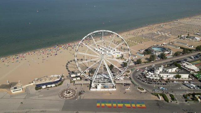 Summer Drone Footage of Crowded Rimini Beach with Ferris Wheel and City Skyline Italy