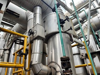 a dense network of industrial pipes, valves, and machinery covered in insulation and metal...