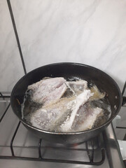 Fried fish in a pan on a gas stove, top view