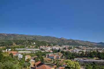 Fototapeta premium Scenic cityscape of Covilha, Portugal with residential buildings, mountains, and clear blue sky.