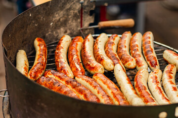Grilled sausages sizzling on barbecue grill, showcasing a variety of textures and colors, with smoke rising in the air, creating a delicious and inviting atmosphere for outdoor gatherings