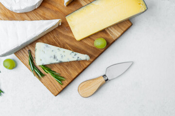 Exploring a variety of cheeses on a wooden board with fresh herbs and grapes