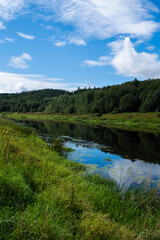 Obraz premium Calm river flowing through Russian countryside with reflections of trees in clear water. Peaceful rural landscape capturing natural beauty, tranquility, and summer outdoor scenery.