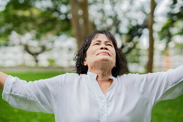 An elderly woman is enjoying the peace and quiet in a park. 
