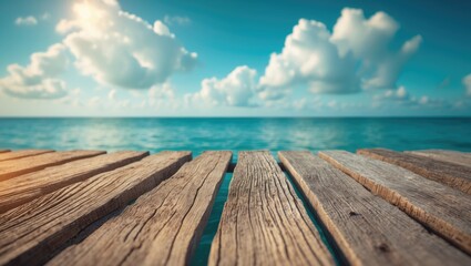 Fototapeta premium A view of a wooden pier leading towards the ocean with a partly cloudy sky; a peaceful seaside scene.
