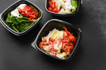 Assorted fresh salads in black containers with gourmet ingredients for meal prep or healthy catering concept