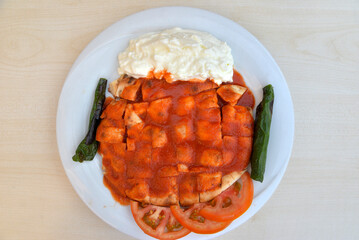 Traditional turkish iskender kebab in copper plate with yogurt, grilled tomatoes and fresh vegetables.