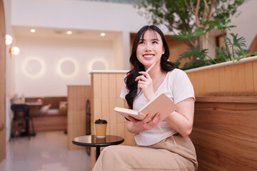 Asian adult woman thinking writing planning new ideas in cozy modern cafe remote workspace for productive work inspiration