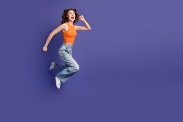 Beautiful and lively young woman in casual wear leaping joyfully with a vibrant purple background and stylish look