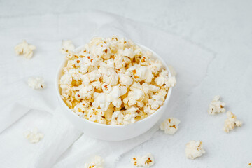 Delicious freshly popped popcorn served in a white bowl on a light background