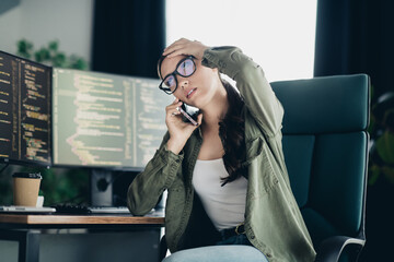 Young programmer working on multiple monitors and dealing with a phone call in a modern casual workspace