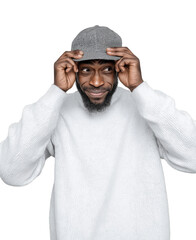 A man with a beard, wearing a white sweater, tries to put on a cap while looking to the side with a playful expression, isolated on a transparent background.