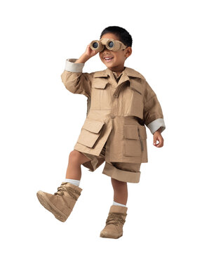 An Asian boy, dressed in a handmade explorer outfit and holding cardboard binoculars, stands and smiles, isolated on a transparent background.