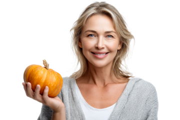 Mature woman holding small orange pumpkin and smiling