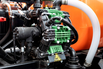 Close-up of industrial pump with green and black components, orange background.