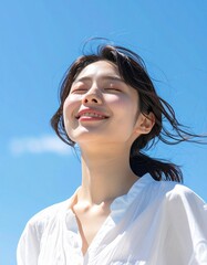 快晴の中で髪を風になびかせた若い日本人女性,A young Japanese woman with her hair blowing in the wind under a clear blue sky.