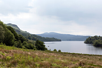 View of Loch Katrine looking south east from the shore path near Portnellan to distant Beinn Bhreac. Loch Lomond and the Trossachs National Park, Southern Highlands of Scotland.