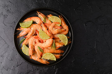 Bowl of cooked shrimp with lime on black background for seafood restaurant or gourmet menu concept