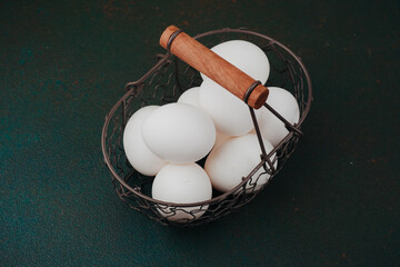 White chicken eggs in rustic wire basket concept for farm fresh food or breakfast ingredient photography