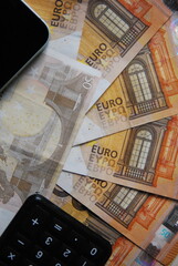 Euro banknotes, phone and calculator on the table
