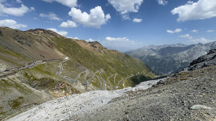 A panoramic view of the winding mountain roads of the famous Stelvio Pass, set against a backdrop...