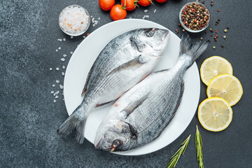 Raw dorado fish with tomatoes lemon herbs and spices on white plate