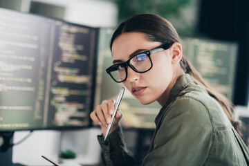 Focused female programmer working on computer in a modern workspace with screens showcasing lines of code