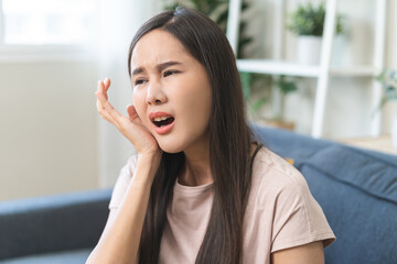 Obraz premium Sensitive teeth, health care concept. Teeth pain and dentistry asian young woman suffer touching her cheek. Female feeling painful toothache. Unhappy feel bad, diseases in oral, ache nerve and molar.