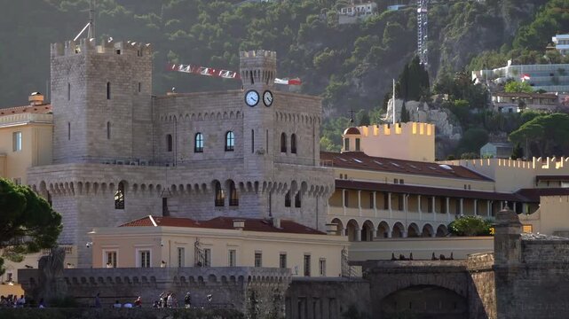 Distant view of the Prince's Palace of Monaco and medieval ramparts perched above Monaco, with visitors walking around