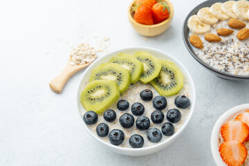 Oatmeal breakfast bowls with fruits and grains on white surface