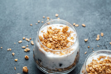Parfaits with granola and yogurt in glass on dark  background