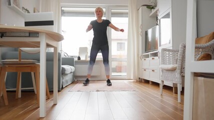 Mature woman following an online fitness tutorial for a remote home workout. Active person training with a virtual coach, enjoying the convenience of exercising on a personal schedule.
